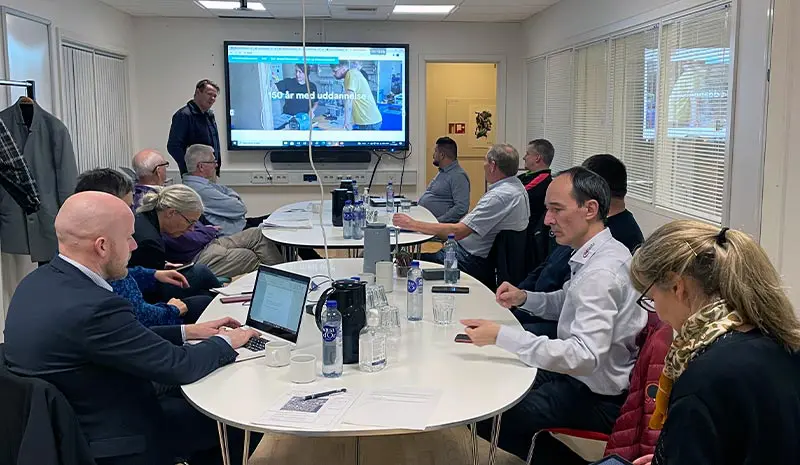 Deltagere samlet omkring et bord til et arbejdsmøde om lokalt erhvervssamarbejde.